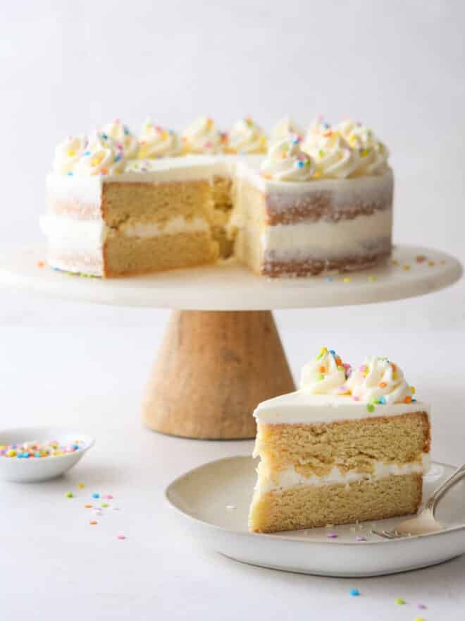 a slice of sugar cookie layer cake with full cake in the background
