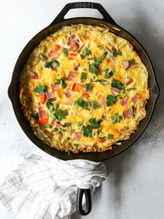 hash brown frittata in cast iron skillet with tea towel
