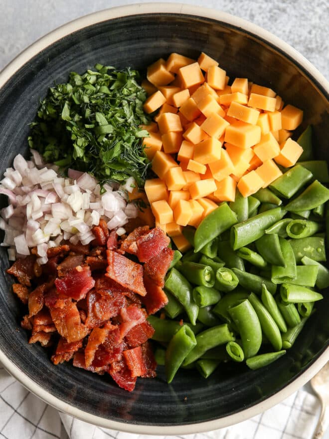 all of the components in a bowl for sugar snap pea salad