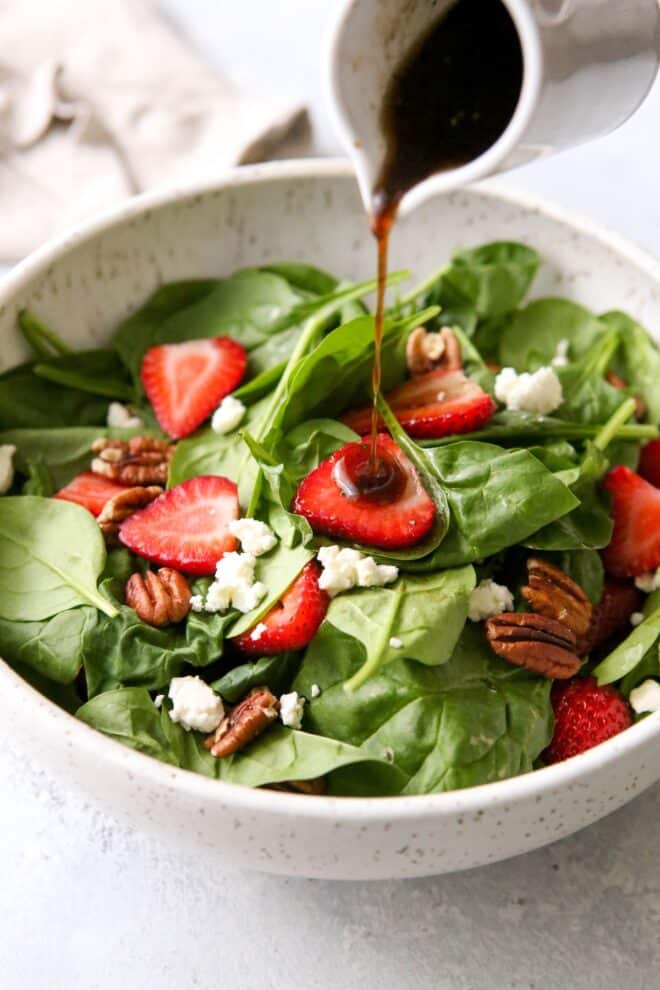 Pouring the warm brown butter dressing over the strawberry spinach salad