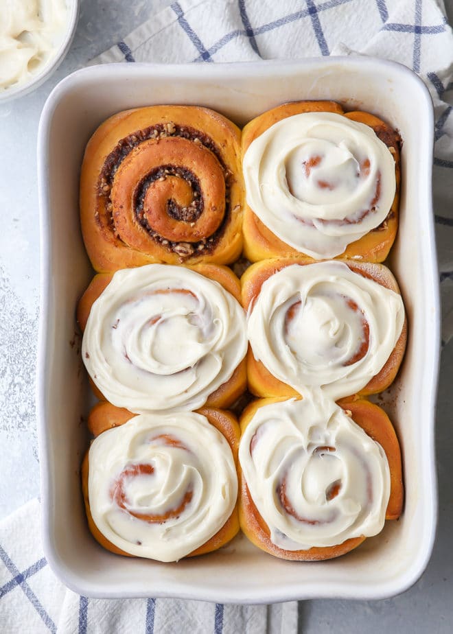 Pumpkin cinnamon rolls filled with a pumpkin spice and pecans and topped with a cream cheese frosting