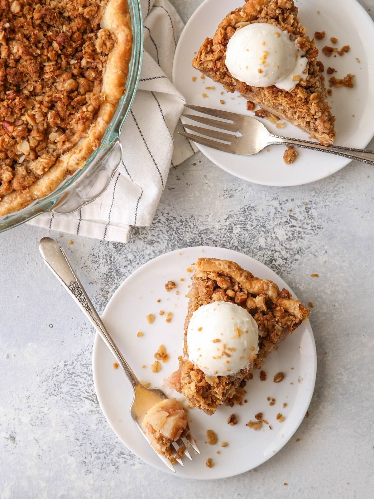 Two slices of pie on plates with a scoop of ice cream on top.