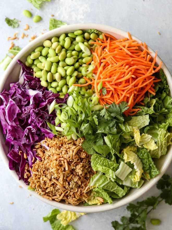 This Asian ramen cabbage salad is filled with napa and purple cabbage, shredded carrots, scallions, shelled edamame, crunchy ramen noodles, slivered almonds and a peanut sesame dressing.