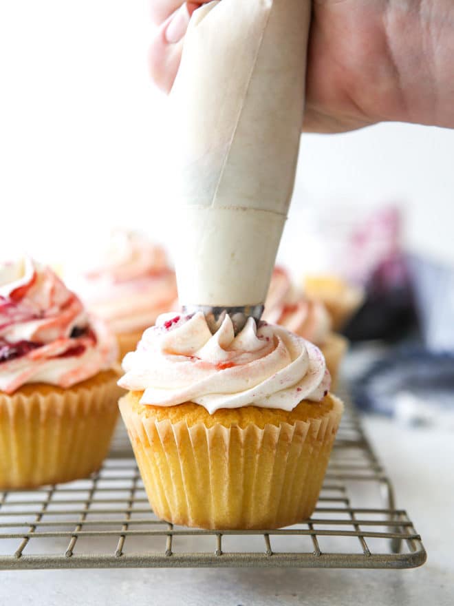 Delicate vanilla cupcakes topped with buttercream frosting swirled with berry preserves are lovely and delicious!