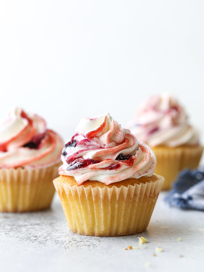 Delicate vanilla cupcakes topped with buttercream frosting swirled with berry preserves are lovely and delicious!