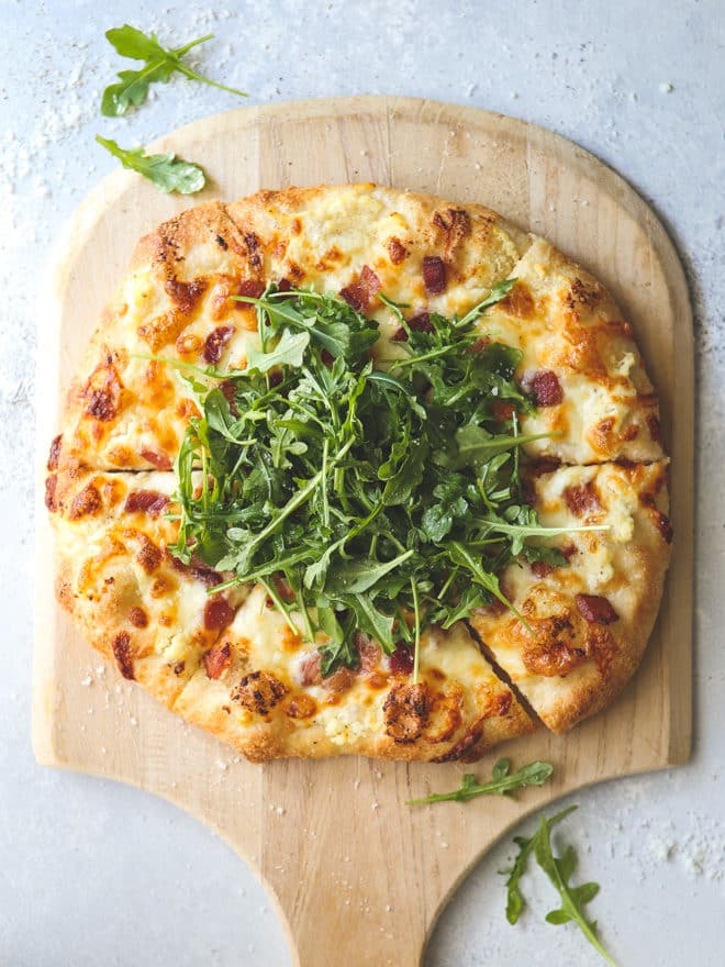 This simple but irresistible three-cheese white pizza is topped with crispy bacon and fresh arugula for maximum flavor.