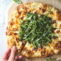 This simple but irresistible three-cheese white pizza is topped with crispy bacon and fresh arugula for maximum flavor.