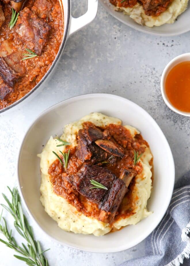 A bowl of beer-braised beef short ribs on top of a bed of mashed potatoes.