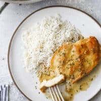 taking a bite of skillet chicken with sauce and rice
