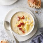 cheesy corn chowder in a bowl with a baguette
