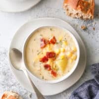 cheesy corn chowder in a bowl with a baguette