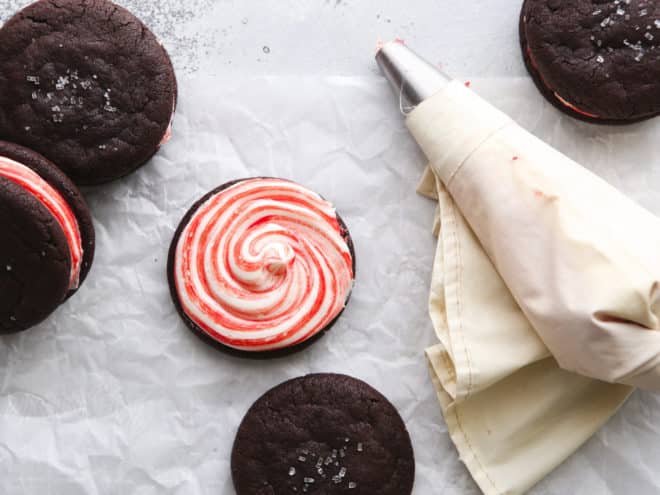 piping candy cane frosting onto a chocolate cookie