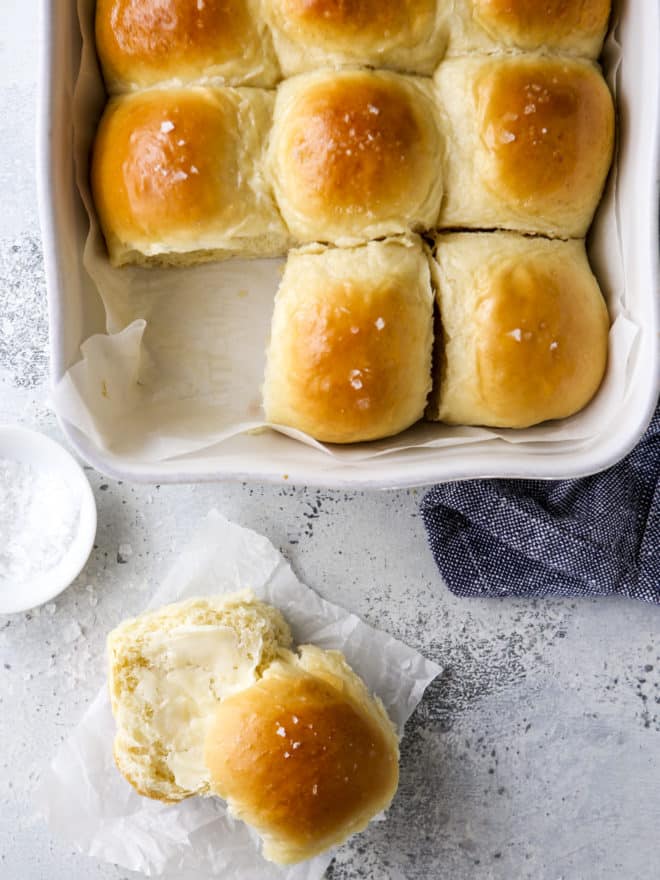 soft white dinner rolls in pan and sliced with butter
