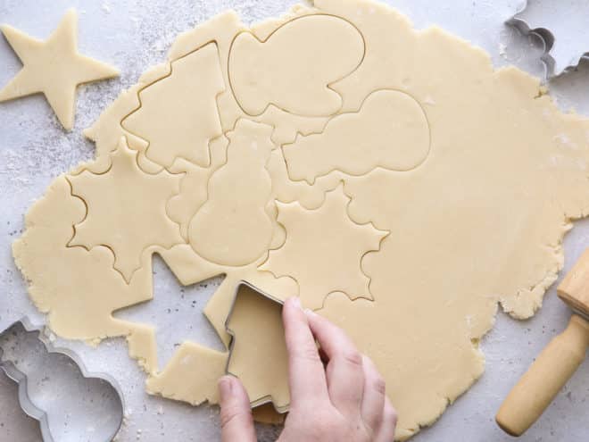 cutting out rolled cookie dough with christmas cookie cutters