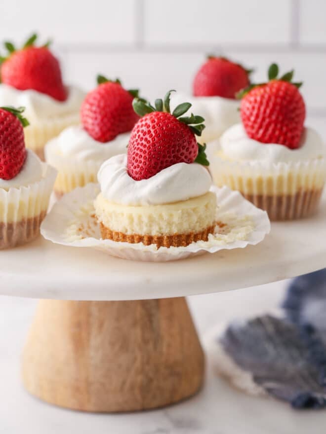 mini cheesecakes on cake stand, one with wrapper pulled down