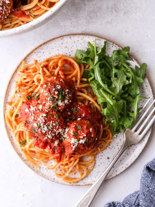 spaghetti and meatballs on a plate with salad