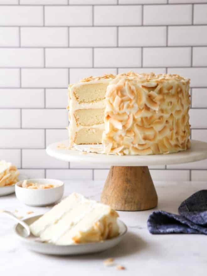southern coconut cake on a cake stand with a slice on a plate