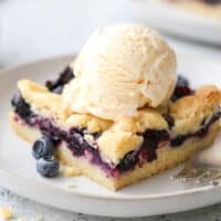 blueberry pie bars with a scoop of ice cream on a plate