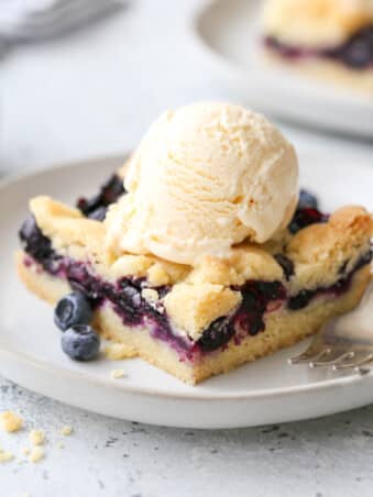 blueberry pie bars with a scoop of ice cream on a plate
