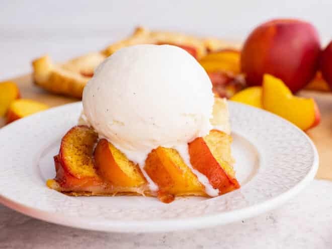 puff pastry tart with peaches and a scoop of vanilla ice cream on a plate