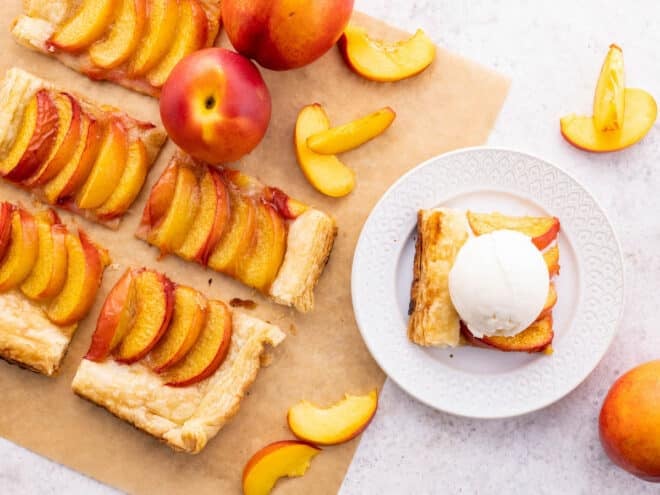 view of sliced summer fruit puff pastry tart with one slice on a plate with vanilla ice cream