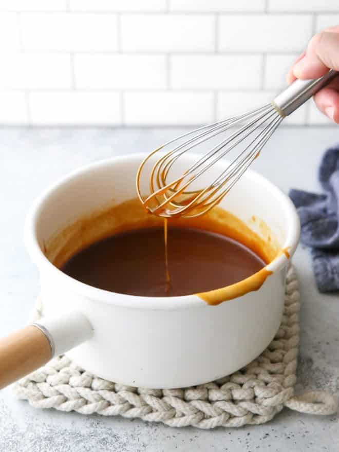 whisking homemade caramel sauce in a pan