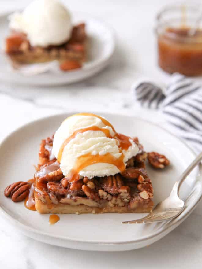 pecan pie bar with ice cream and caramel drizzle on a plate