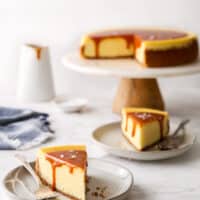 slices of salted caramel cheesecake on a plate with cake stand in background