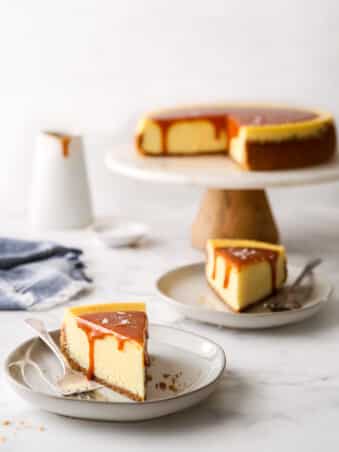 slices of salted caramel cheesecake on a plate with cake stand in background