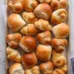 a sheet pan filled with different shapes and flavors of dinner rolls