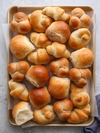 a sheet pan filled with different shapes and flavors of dinner rolls