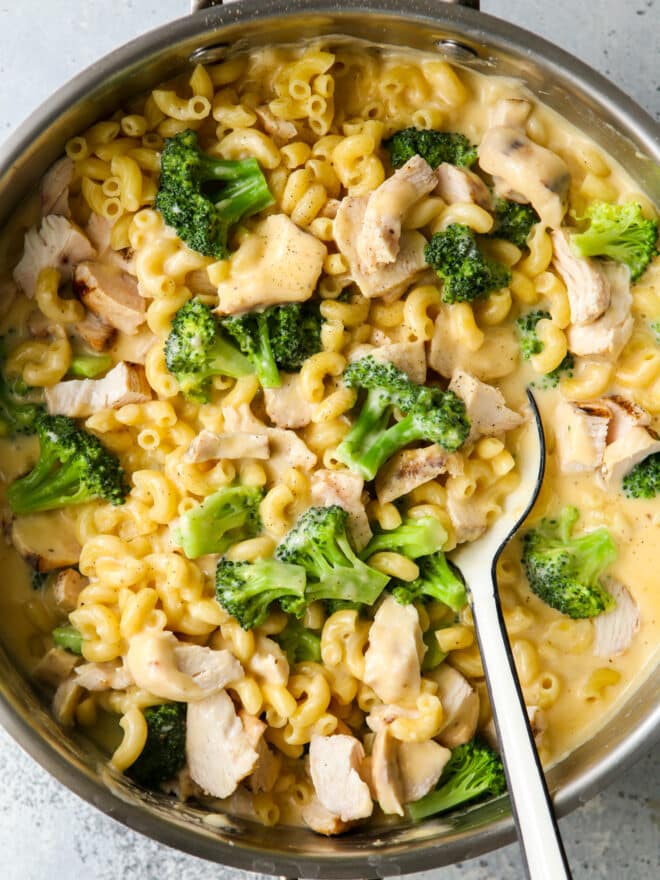 stirring chicken broccoli macaroni and cheese with a large spoon