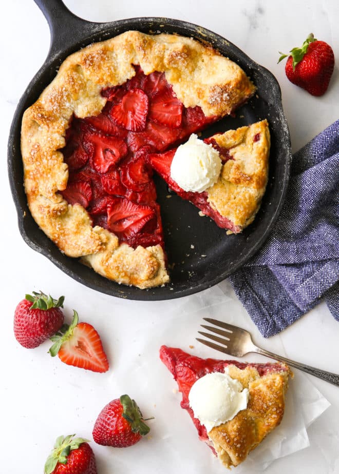 strawberry skillet pie with a slice on the side, scoops of ice cream on top