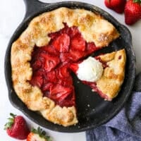 sliced strawberry skillet pie with a scoop of vanilla ice cream on a slice of pie