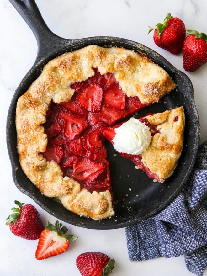 sliced strawberry skillet pie with a scoop of vanilla ice cream on a slice of pie