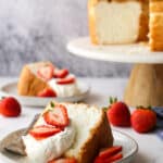 closeup of angel food cake with whipped cream and strawberries on a plate