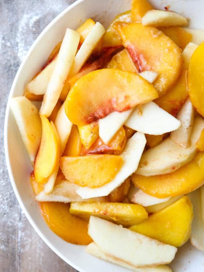 mixing peaches and apples in a bowl