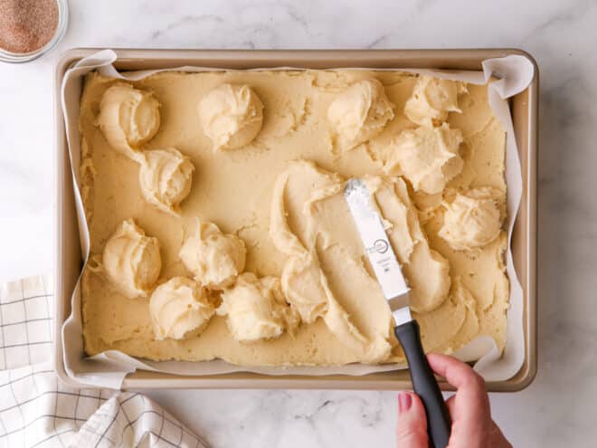 spreading gooey butter layer over cookie base with spatula