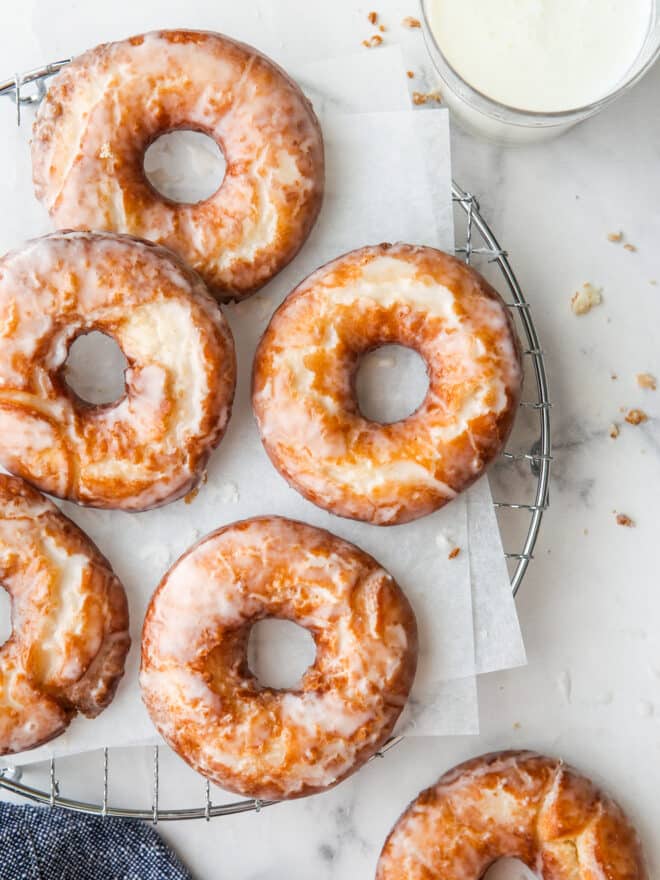 glazed old fashioned doughnuts on a wire rack with glass of milk