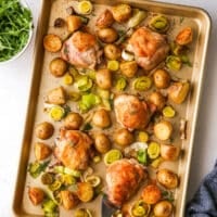 one-pan roasted chicken and potatoes with bowl of arugula and yogurt dill sauce