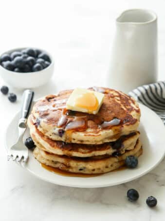 stack of blueberry pancakes with butter and maple syrup
