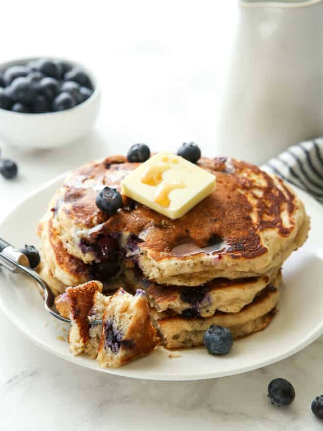 stack of blueberry pancakes with bite on a fork