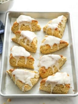 vanilla bean scones with frosting all on a baking sheet pan