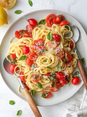 lemon pasta with tomatoes and basil on a plate in utensils