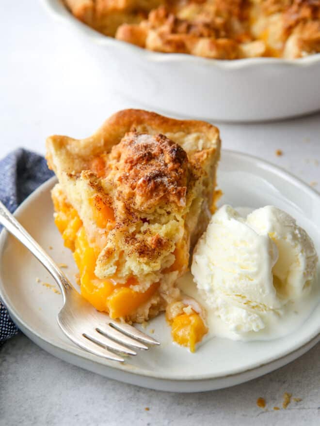 closeup of peach cobbler pie on a plate with ice cream