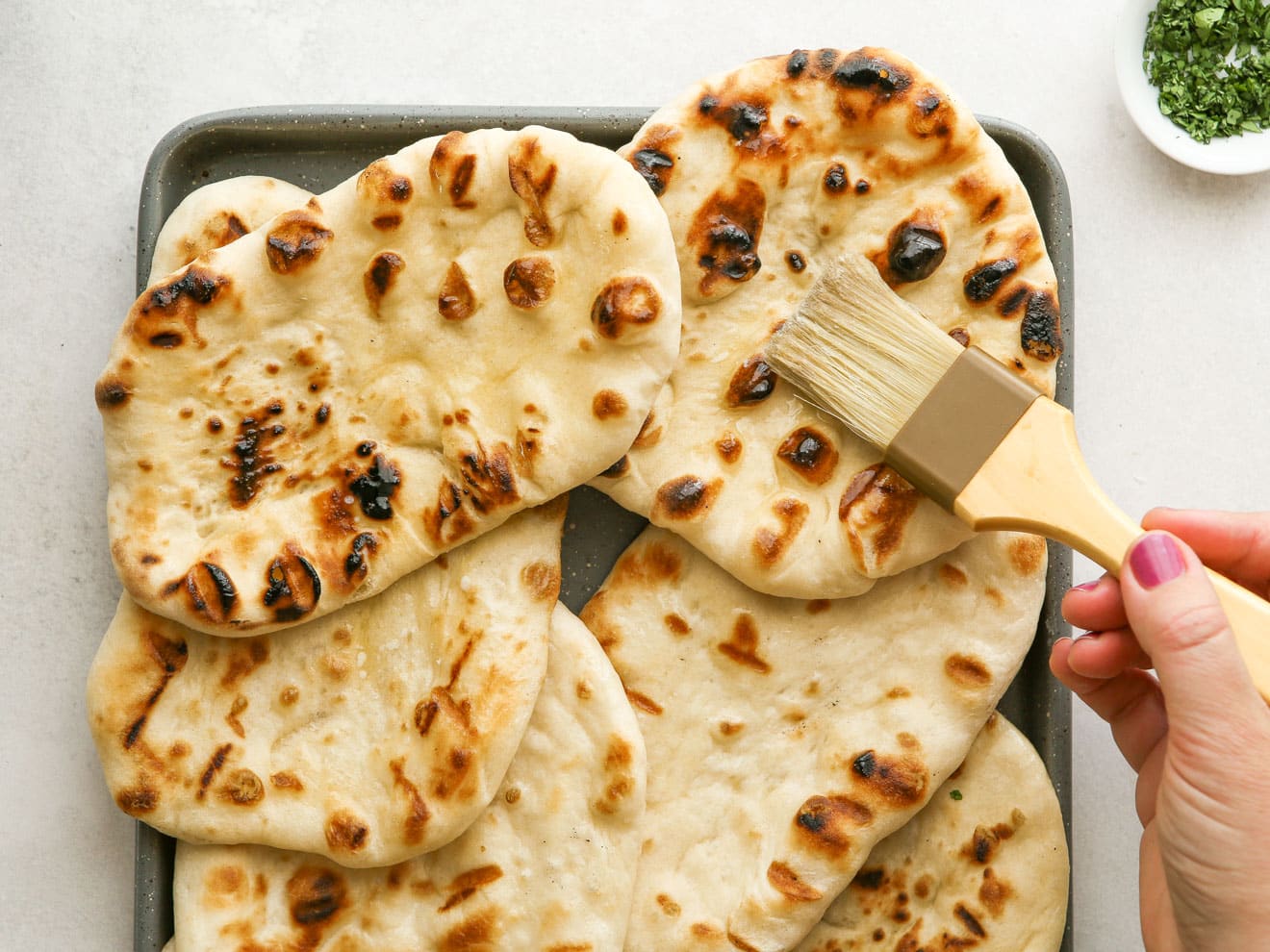brushing grilled flatbread with butter