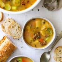 potato leek and italian sausage soup in bowls with crusty bread