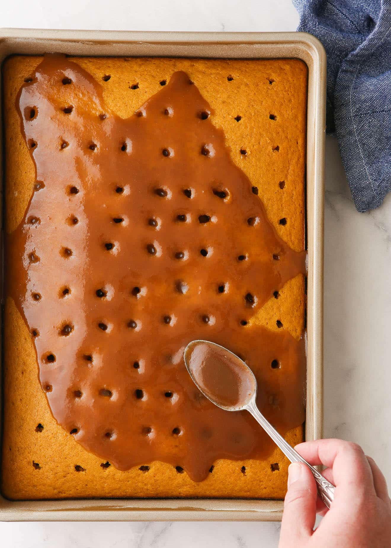 pouring caramel over pumpkin cake with holes in in