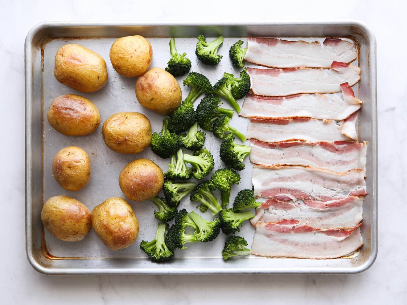 adding broccoli and bacon to the sheet pan