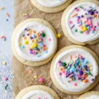 frosted sugar cookies with sprinkles on parchment paper